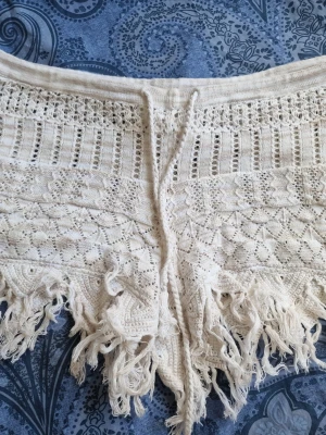 Cremefärgade strand-shorts från Odd Molly  - Virkade romantiska shorts med fransar nedtill och dragsko i midjan. Perfekta för stranden i sommar eller för en bohemisk vibe för festivaler🤍