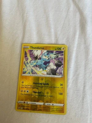 Pokémonkort Thundurus - Säljer ett Pokémonkort med Thundurus, gul ram och färgstark illustration. Kortet har 120 HP och attacker som Assisting Spark och Thunder. Perfekt för samlare eller dig som vill stärka din lek med en el-typ Pokémon.
