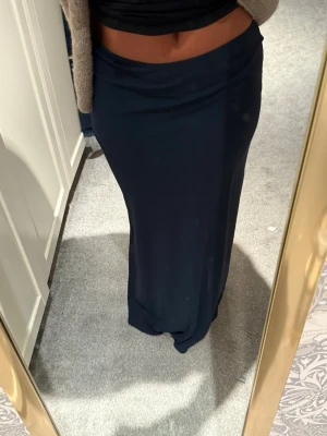 Mörkblå långkjol i mjukt material - Säljer en enkel och stilren mörkblå långkjol med rak passform. Kjolen är gjord i ett mjukt och följsamt material som sitter snyggt på kroppen. 