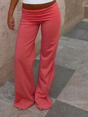 Trendiga coral pants - Snygga vida leggings i en härlig rosa färg med låg midja och bred linning. Stretchigt material som sitter bekvämt och följer kroppen. Perfekta för en trendig och avslappnad look.