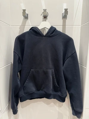 Lager 157 Mörkblå Hoodie - En stilren mörkblå hoodie med luva och stor magficka framtill. Hoodien har ribbade muddar vid ärmslut och nederkant samt en avslappnad passform. Perfekt för en casual look och enkel att matcha med andra plagg.