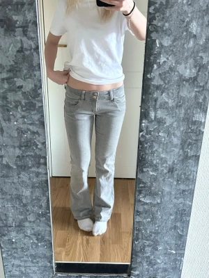 Grå bootcut jeans med låg midja - Säljer ett par gråa bootcut jeans med låg midja. Jensen är bootcut, och två knappar framtill. Storleken är 158 men skulle säga XS då det är väldigt stretchiga☺️jag är 164cm lång