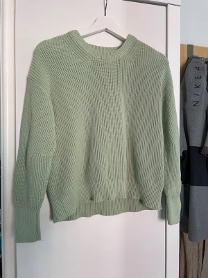 Ljusgrön stickad tröja - En stickad tröja i ljusgrönt med grov ribbstickning och rund hals. Tröjan har långa ärmar och breda muddar vid ärmslut och nederkant. Perfekt för lager-på-lager och chill dagar.