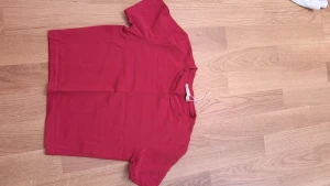 Röd t-shirt från Zara - En enkel och stilren röd t-shirt från Zara i storlek S. T-shirten har korta ärmar och en klassisk rund halsringning. Perfekt för en avslappnad look och lätt att matcha med andra plagg.