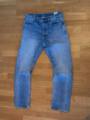 G-star raw ljusblå raka jeans - G-Star Raw jeans i ljusblå tvätt med rak passform och hög midja. Femficksmodell med knappgylf. Tillverkade i slitstark bomullsdenim. Perfekta för en avslappnad och tidlös stil.Pris går att diskuteras om du har frågar är de bara att skriva ett meddelande till mig 