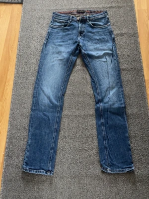 Blå jeans från Massimo Dutti - Snygga blå jeans från Massimo Dutti med klassisk femficksdesign och raka ben. Jeansen har kontrastsömmar och detaljer som röd söm vid knapphålet. Perfekt för dig som gillar stilrena och tidlösa jeans i denim.