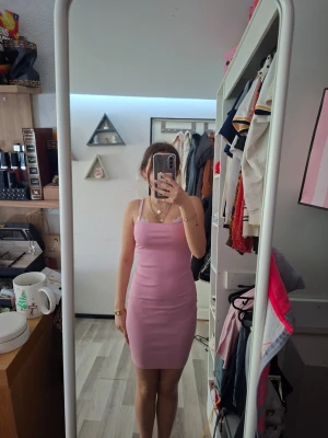 Rosa tight kortklänning med smala axelband - Säljer en söt rosa kortklänning med smala axelband och figurnära passform. Klänningen har enkel design och är perfekt för dig som gillar en stilren look. Materialet känns mjukt och stretchigt, vilket gör den bekväm att bära. Aldrig använd.