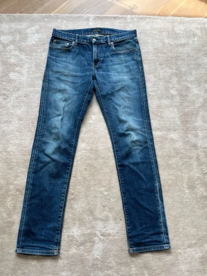 Blå raka jeans med slitningar - Snygga blå jeans med raka ben och diskreta slitningar på framsidan. Klassisk femficksmodell med knapp- och dragkedjegylf. Perfekta för en avslappnad och trendig look. Materialet är denim i bomull.