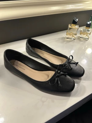 Svarta ballerinaskor  - Stilrena svarta ballerinaskor från Carin wester med klassisk rosett framtill. Använda endast en gång. 