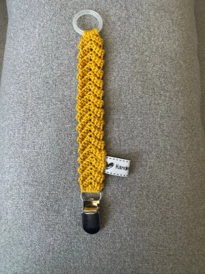 Virkad napphållare  - Virkad, saffransgul napphållare, virkad av mig i 100% bomullsgarn med metallclips och silikonring.  Mönsterskapare: animo.design 