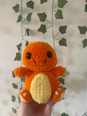 Virkad charmander  - Supergullig handvirkad Charmander i orange och gul plysch med stora svarta ögon och en liten eldsvans. Perfekt som dekoration eller present till Pokémon-fans. Mjuk och fluffig, lätt att krama och ha med sig överallt.