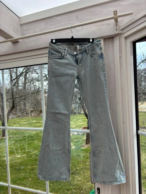 Ljusblå bootcut jeans - Säljer ett par ljusblå bootcut jeans med klassisk femficksmodell och normal midja. Jeansen har en snygg tvättad look och är tillverkade i mjukt denimtyg. Perfekta för dig som gillar retrostil och vill ha ett par jeans med lite vidare ben.