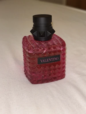 Valentino parfym Born in Roma Extradose 30 ml - Säljer en lyxig parfym från Valentino i en snygg rosa glasflaska med nitar och svart lock. Flaskan har en cool, rutmönstrad design som verkligen sticker ut på hyllan. Perfekt för dig som gillar exklusiva dofter och vill ha något unikt i din samling. Luktar lite kokos men man känner även den originala born in Roma. En sommarparfym skulle jag säga! 🌴🥥 