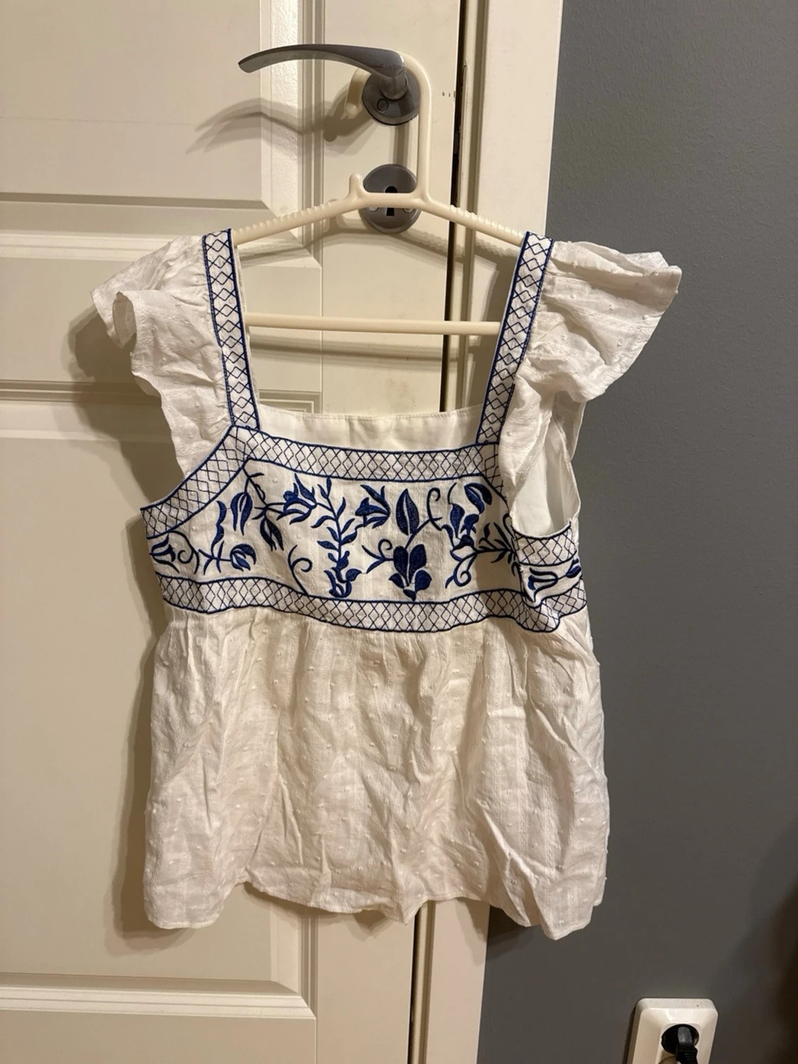 Vit blus med blå broderi och volang