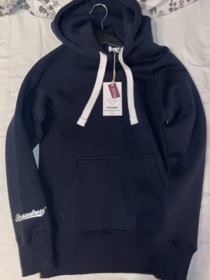 Mörkblå Russemerch hoodie  - Jag säljer en mörkblå hoodie ifrån Russemerch som har ett skönt och bekvämt material. Tröjan är helt ny och aldrig använd. Det är bara att skriva om ni har frågor och är intresserade😁🙌🏼