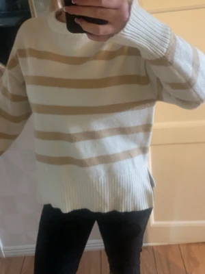 Beige och vit randig stickad tröja - Säljer en stickad tröja med breda beige och vita ränder. 