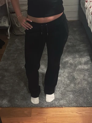 Svarta Juicy Couture - Säljer ett par svarta Juicy Couture med raka ben och dragsko i midjan. Byxorna har fickor fram och bak, samt silverfärgade detaljer på bakfickorna. Perfekta för chill dagar och riktigt sköna att ha på sig. Kan ge en snygg look på vardagen med en skön passform 🩷🙏🏻😍💝lite slitage på byxbenet nedtill pågrund av att de va för långa men annars inga problem 🥰ni kan komma med pris alternativ jag sätter bara ett startpris i annonsen, vill bara bli av med de