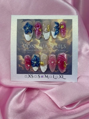 Shell (M);Medium Almond - Unika handgjorda press-on naglar i en medium lång mandelform. Setet har en mix av rosa och nude baser med vita french detaljer, 3D-blommor i blått och guldiga dekorationer. Handgjorda med coola 3Dswirl-mönster och pärlor för en riktigt statement look.M: 16 mm, 12 mm, 12,5 mm, 11,5 mm, 10 mm