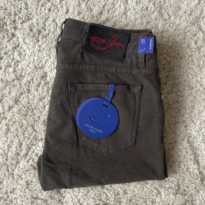 Jacob Cohën ”Special Edition” mörkgråa– Stl 31 (Helt nya) - Säljer ett par feta limted edition helt nya och oanvända lyxbyxor från Jacob Cohën. Handgjorda i Italien med fantastisk kvalitet och passform. Nypris över 5500kr säljer för 1480kr  Modell: Style 622 Special Edition (exklusivare detaljer & tyg).  • Färg: Mörkgrå med lite brunt inslag.  • Skick: 10/10 – Helt nya med tags.  • Storlek: 31 Waist.  Mått: • Midja: 87 cm omkrets. (Kolla bild) • Längd: 107 cm.