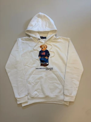 Vit Ralph lauren polo bear hoodie S - Vit Ralph Lauren Polo bear hoodie //  Mycket bra skick aldrig använd //  Storlek S //  Mått  Längd 63 Axelbredd 45cm  Bredd mellan armhålorna 50cm  Armlängd 58cm  Skriv vid minsta fråga eller fundering🤝