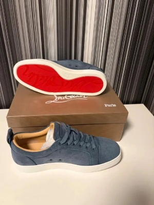 Blåa Louboutin sneakers i mocka - Äkta snygga blåa sneakers från Christian Louboutin i mjuk mocka med klassisk röd sula och vita kanter. Skorna har lågt skaft, matchande blå skosnören och beige innersula i läder. Perfekta för dig som vill sticka ut med exklusiv stil.
