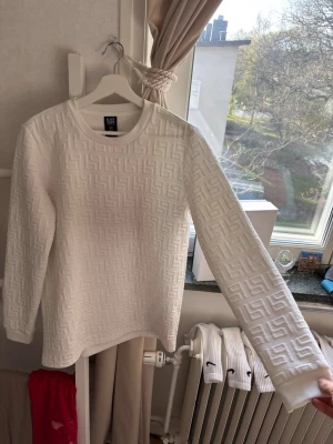 Vit sweatshirt  - Säljer en vit sweatshirt från SIKSILK med upphöjt geometriskt mönster över hela tröjan. Tröjan har rund halsringning och långa ärmar. Perfekt för dig som gillar stilrena och moderna plagg med en twist.