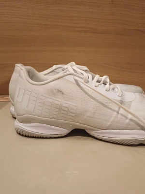 Vita sneakers från Puma - Säljer ett par stilrena vita sneakers från Puma med diskret logga på sidan. Skorna har lågt skaft, snörning och en sportig sula med ProFoam-teknologi. Tillverkade i mesh och syntetmaterial för en lätt och luftig känsla. Perfekta för dig som gillar minimalistisk stil.