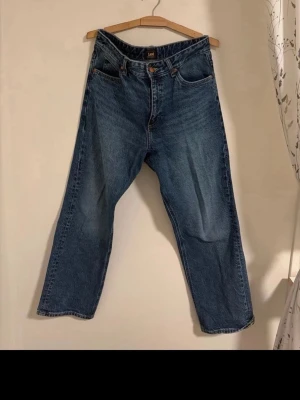 Blå raka jeans från Lee - Klassiska blå jeans från Lee med rak passform och hög midja. Jeansen har fem fickor, gylf med dragkedja och knapp samt Lee-logga på bakfickan och bak i linningen. W31L31