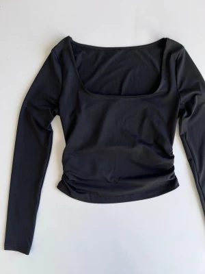 Svart y2k stretchig långärmad topp med fyrkantig urringning, stl S - Y2K svart långärmad topp med fyrkantig urringning och tight passform och mycket stretch. Lite croppad och sitter riktigt skönt mot kroppen och är perfekt till ett par jeans. Storlek S.