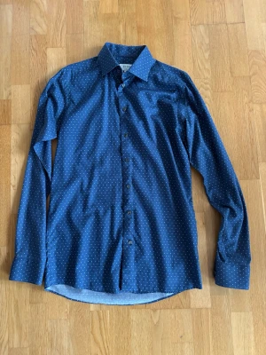 Blå prickig skjorta från Eton - Snygg blå skjorta från Eton med vita prickar och klassisk krage. Skjortan har lång ärm, knappar framtill och är i slim fit. Tillverkad i bomull för en skön känsla och stilren look.