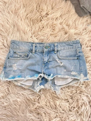 F20 Ljusblåa lowrise lågmidjade jeanshorts med blå färg fläckar - Sååå snygga! Midja ca 37 cm rakt över
