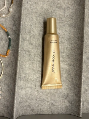 LH cosmetics  - Flytande highlighter från LH cosmetics i nyansen Warm Glow. Tuben är guldig och smidig att använda för att ge ansiktet en snygg lyster. Perfekt för att framhäva kindben och ge huden ett fräscht glow.