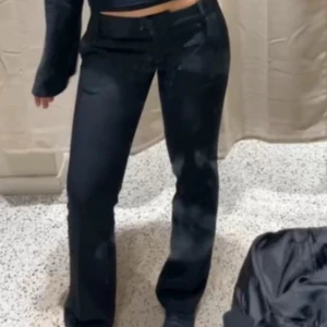 Svarta bootcut jeans med låg midja - Snygga svarta bootcut jeans med låg midja och klassisk femficksdesign. Jeansen har en något utsvängd passform nertill och stängs med knapp och dragkedja. Perfekta för en trendig och avslappnad look.