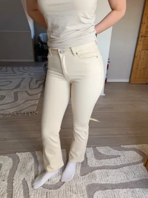 Krämvita raka jeans från Vero Moda  - Säljer ett par krämvita jeans från Vero Moda med rak passform och hög midja. Jeansen har klassisk femficksdesign, bälteshällor och stängs med knapp och dragkedja. Storlek S/30. Använd en-två gånger. 