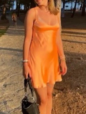 Zara orange satin klänning med smala axelband - Populär kort klänning i persikofärgad satin med smala axelband och figurnära passform. Klänningen har en enkel, stilren design och är perfekt för varma dagar. Lätt skimrande material ger en lyxig känsla. Bra skick, skriv för egna bilder eller andra frågor😊💗💗