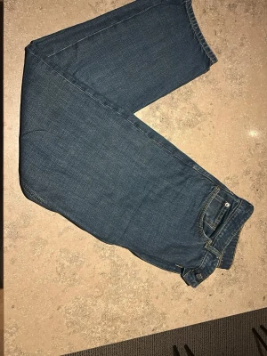 Mörkblå raka jeans - Säljer ett par klassiska mörkblå jeans med rak passform och kontrastsömmar. Jeansen har normal midja, fem fickor och stängs med knapp och dragkedja. Perfekta till vardagslooken och tillverkade i slitstarkt denimtyg.