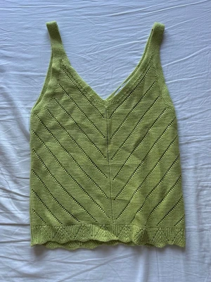 Stickad grön linnetopp med v-ringning - Snygg stickad linnetopp i ljusgrön färg med v-ringning och breda axelband. 