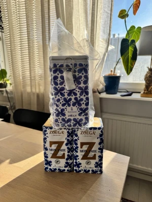 Rörstrand Mon Amie kaffeburk + Zoégas kaffe - Säljer en snygg kaffeburk från Rörstrand i Mon Amie-serien med blått blommönster och metallspänne. Medföljer två paket Zoégas Mon Amie-kaffe. Perfekt för dig som gillar design och kaffe. Burken är i plåt och har klassisk retrostil.