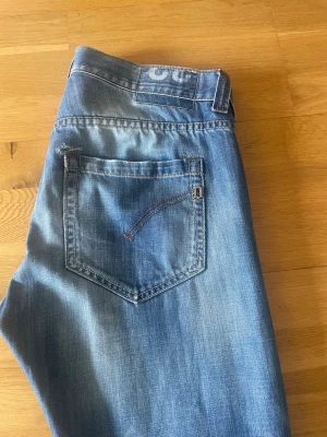 Ett par lite schysstare dondups - Säljer ett par blåa dondups med raka ben och snygga slitningar på låret. Jeansen har klassisk femficksdesign och kontrastsömmar. Materialet är denim i bomull och passformen är avslappnad men ändå stilren. Perfekta för en casual look.