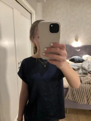 Mörkblå t-shirt  - En superfin mörkblå t-shirt med rund hals och korta ärmar. Perfekt för dig som gillar en look med något lite extra då den har olika tyg fram- och bak. Funkar till jeans eller shorts. Materialet är mjukt och känns skönt mot huden.