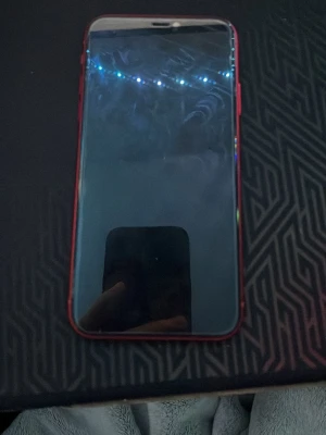 Röd iPhone 11 med dubbla kameror - Säljer en snygg röd iPhone 11 från Apple. Telefonen har en stilren design med glasbaksida, rundade kanter och dubbla kameror på baksidan. Perfekt för dig som gillar färg och vill ha en mobil med bra kamera och modern look.