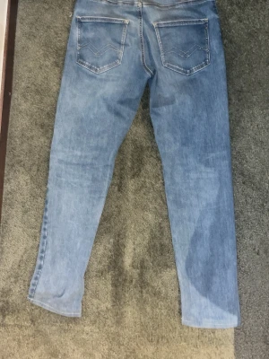 Ljusblå slim fit  jeans från replay - Säljer ett par ljusblå slim fit jeans från replay  med klassisk femficksdesign och snygga bakfickor med dekorativa sömmar. Jeansen har normal midja och är tillverkade i stretchigt denim för en bekväm passform.