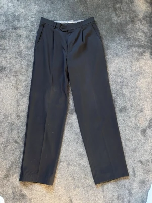 Svarta raka kostymbyxor - Stilrena svarta kostymbyxor med rak passform och pressveck. Byxorna har sidofickor och hällor för bälte. Perfekta för en clean och klassisk look. Materialet känns mjukt och följsamt.