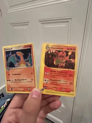Pokémonkort Charizard & Charmeleon - Två Pokémonkort: Charizard och Charmeleon. Båda korten har klassisk gul ram och färgstarka illustrationer av eld-Pokémon. Text och symboler i svart, rött och vitt. Perfekt för samlare eller Pokémon-fans som gillar originaldesignen.