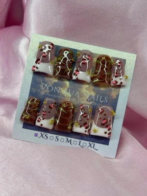 Kira (XS); Medium Duck Nails - Unika handgjorda press-on naglar  i brun och vit färg med trendigt ko-mönster och små guldfärgade detaljer. Naglarna har en duck nail form och är handgjorda. Perfekt för dig som vill ha en cool och personlig nagelstil.XS: 14 mm, 11 mm, 11,5 mm, 10 mm, 8 mm 