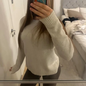 Beige stickad tröja - Mysig ljus beige/benvit stickad tröja med ribbade muddar vid ärmslut och nederkant. Långärmad och i mjukt material som känns skönt mot huden.