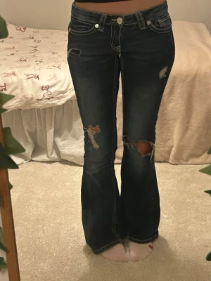 Mörkblå lågmidjade jeans med hål - Snygga lågmidjade jeans jeans med slitna detaljer och hål på knäna. Köpta för 400kr på Gina tricot och är just nu helt slutsålda!Storlek xs, pris kan diskuteras