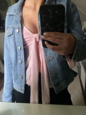 Ljusrosa knytkofta från Gina Tricot - Supersöt ljusrosa kofta från Gina Tricot med långa ärmar och knytband framtill. Tunn och mjuk i materialet, perfekt att slänga över ett linne eller topp. Koftan har en feminin och avslappnad passform.