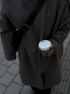 Grå oversized ullkappa med sjalkrage - Säljer en grå oversized kappa med sjalkrage och stora ärmar. Kappan har minimalistisk design och är tillverkad i ullblandning, perfekt för kalla dagar. Passar dig som gillar stilrena och moderna plagg.