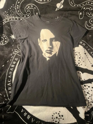 Svart t-shirt med tryck - Cool svart t-shirt med ett stort tryck framtill. Klassisk passform med rund hals och korta ärmar. Perfekt för dig som gillar stilrena plagg med en twist. Materialet känns mjukt och skönt mot huden.